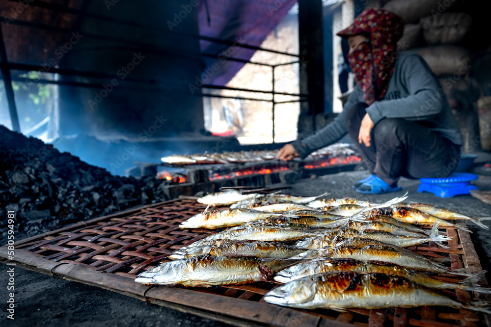 Fishermen grilled fresh fish on embers for sale at markets in Dien Van grilled fish village, Nghe An province, VN