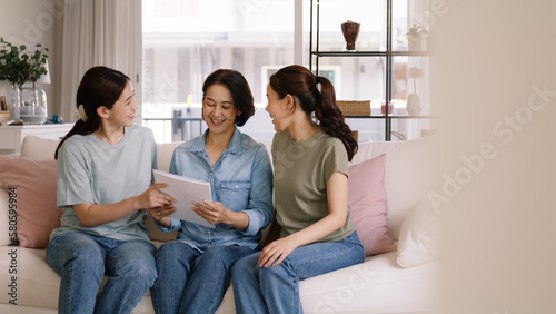 Buy mediclaim health care life insure for older mum. Young adult woman asia people grown up child give gift to middle aged mom reading protect cover saving plan paper smile laugh sitting at sofa home.