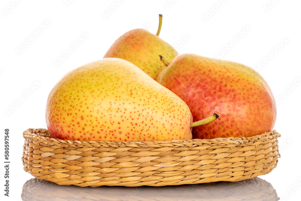Three ripe yellow-red pears on a straw plate, close-up, on a white background.
