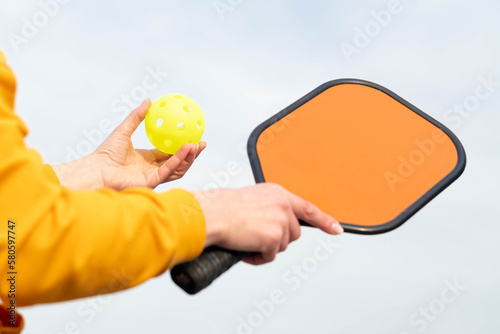 back view pickleball game woman player  hands over blue sky hitting pickleball yellow ball with paddle  outdoor sport leisure activity
