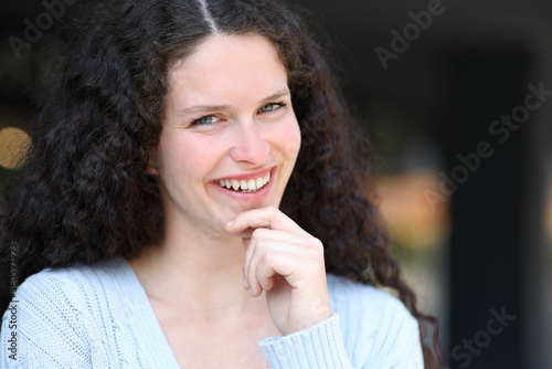 Happy woman smiling with curly hair in the street