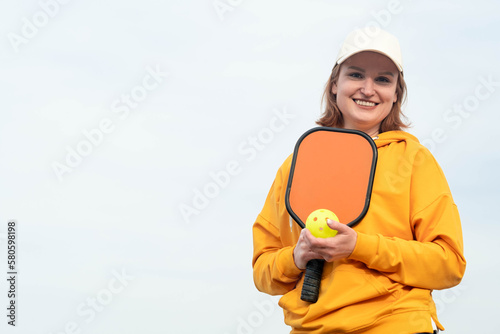 portrait woman player pickleball game over blue sky, pickleball yellow ball with paddle, outdoor sport leisure activity