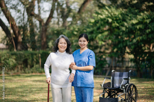 Elderly asian senior woman on wheelchair with Asian careful caregiver. Nursing home hospital garden concept...