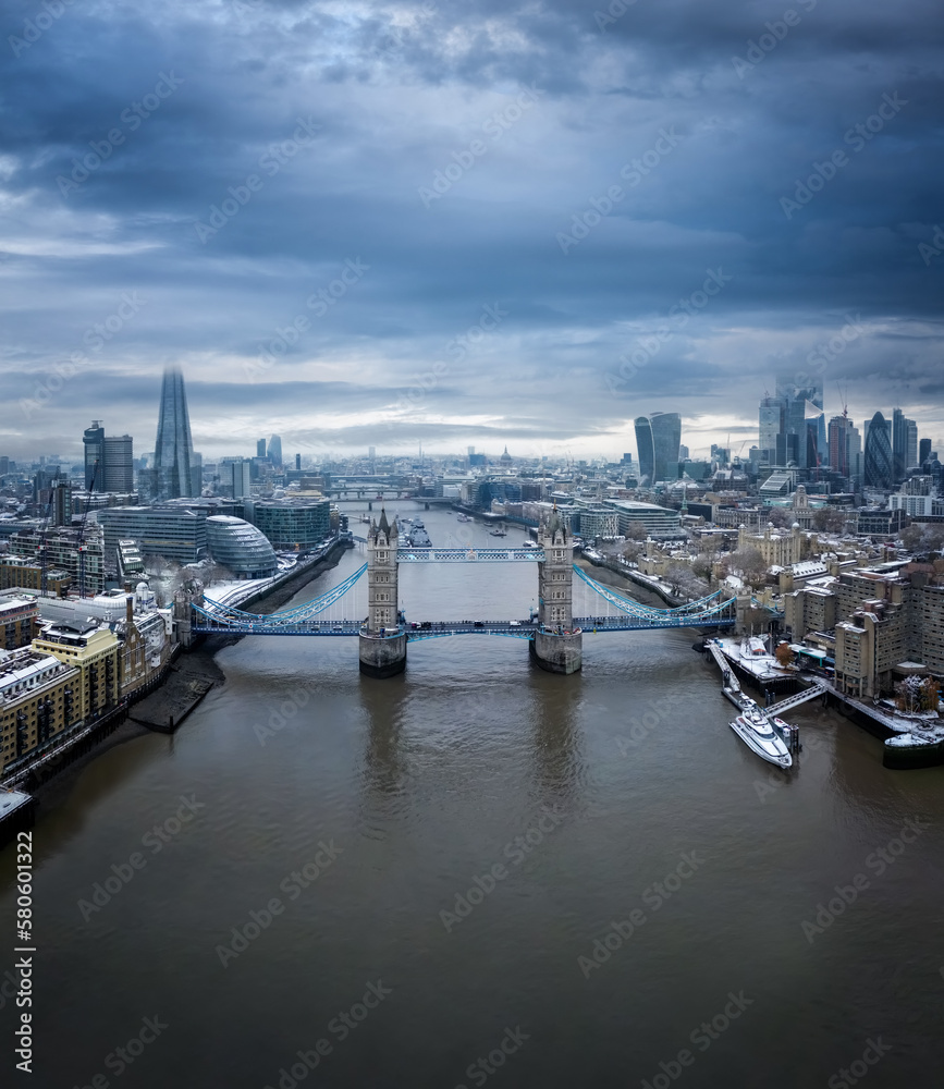 Aerial view of the snow covered skyline of London with Tower Bridge in the front and the skyscrapers of the City behind during a cold winter morning