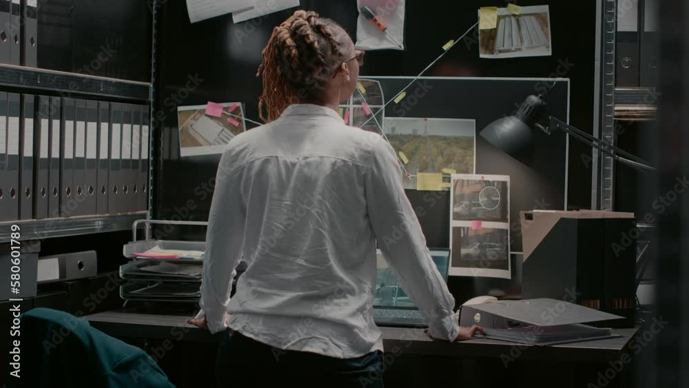 Private investigator examining criminal clues files on map in archive room, reading suspicious information. Law enforcement agent studying forensic evidence to catch crime suspect.