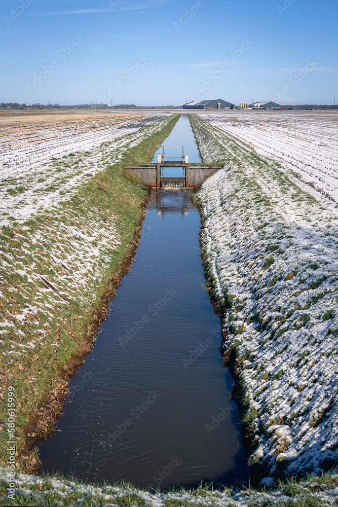 Typical Dutch landscape with meadows, snow, farms, ditches and locks to maintain the water level, province of Drenthe, the Netherlands