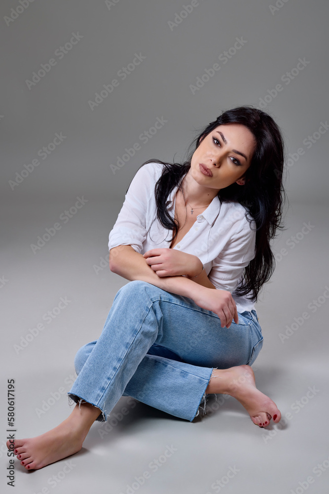 beautiful brunette woman in casual clothes posing in studio on gray background.