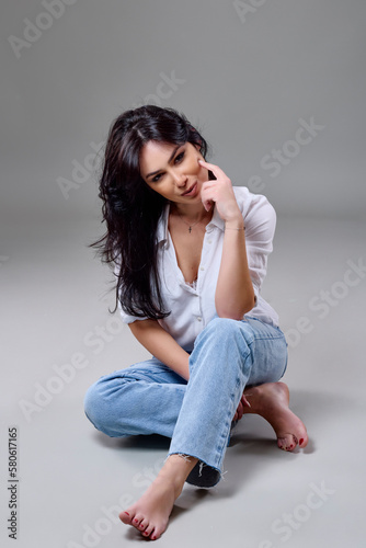 beautiful brunette woman in casual clothes posing in studio on gray background.