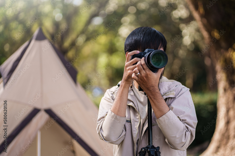 Asian man taking photo by camera enjoying camping outdoors in nature. traveling in the wild Asian man taking photo by camera enjoying camping outdoors in nature. traveling in the wild