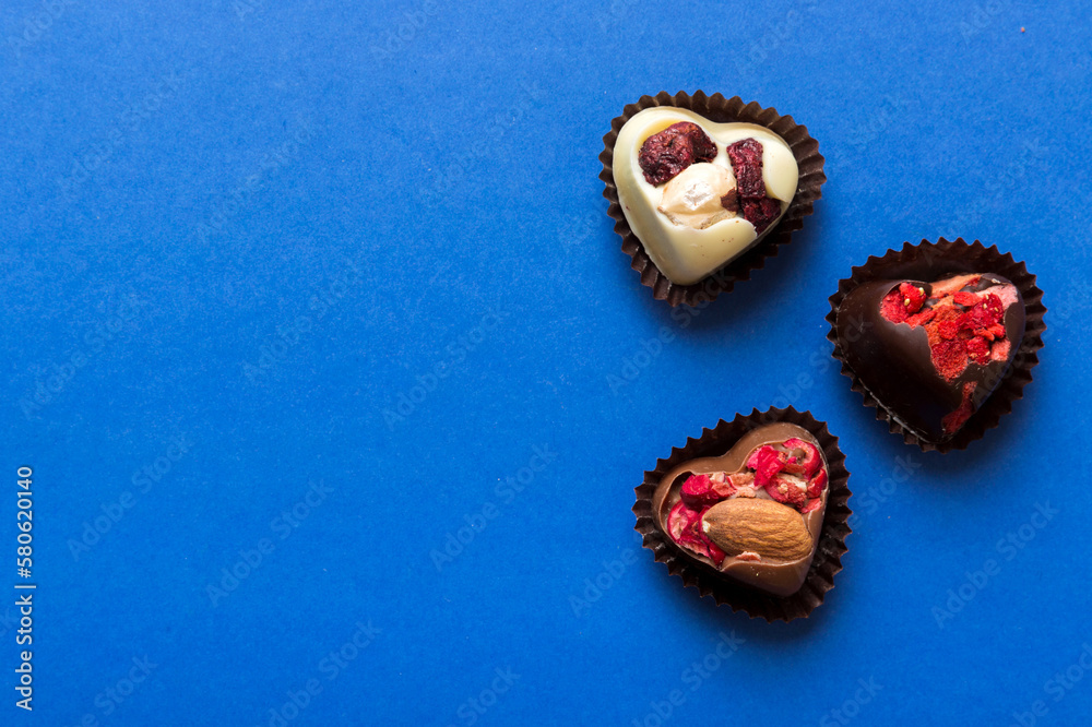 chocolate sweets in the form of a heart with fruits and nuts on a colored background. top view with space for text, holiday concept chocolate sweets in the form of a heart with fruits and nuts on a colored background. top view with space for text, holiday concept