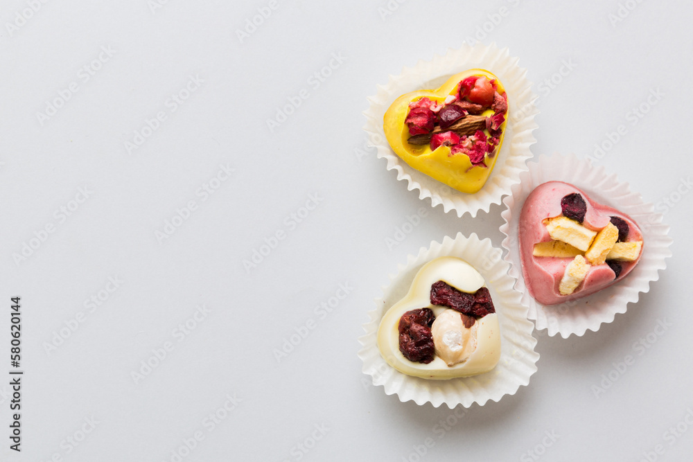 chocolate sweets in the form of a heart with fruits and nuts on a colored background. top view with space for text, holiday concept chocolate sweets in the form of a heart with fruits and nuts on a colored background. top view with space for text, holiday concept