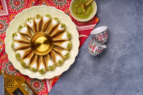 Arabian pancake Qatayef with qishta cream and pistachio . Traditional sweets with ramadan decor . photo