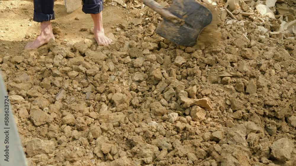 An Asian man collects soil and clay barefoot, revealing the traditional