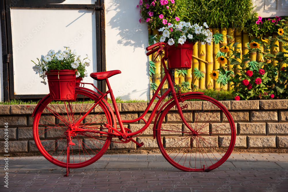Red bicycle with flowers in a garden