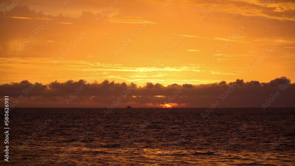 Golden Orange Sunset Over Sea. Sun Disk Hides Behind Seascape Horizon and Courful Purple Clouds Golden Orange Sunset Over Sea. Sun Disk Hides Behind Seascape Horizon and Courful Purple Clouds
