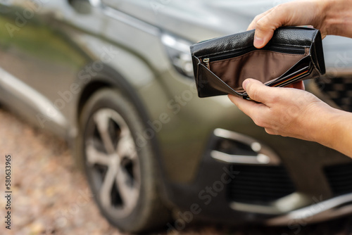 Person holding an empty wallet in the hands stands front car. Insurance, loan and buying car finance concept