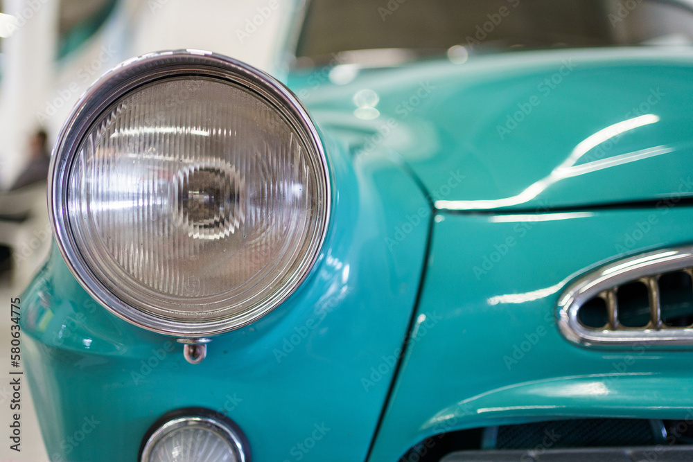 A close up look at teal classic car. Retro automobile exterior scene. Front view of old vehicle.