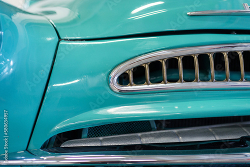 A close up look at teal classic car. Retro automobile exterior scene. Front view of old vehicle.