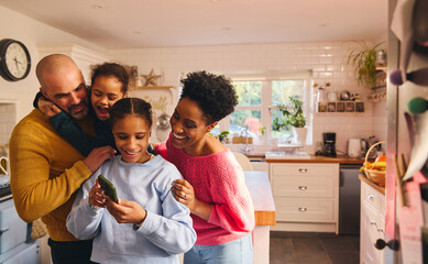 Teen girl looking at selfie on phone with family