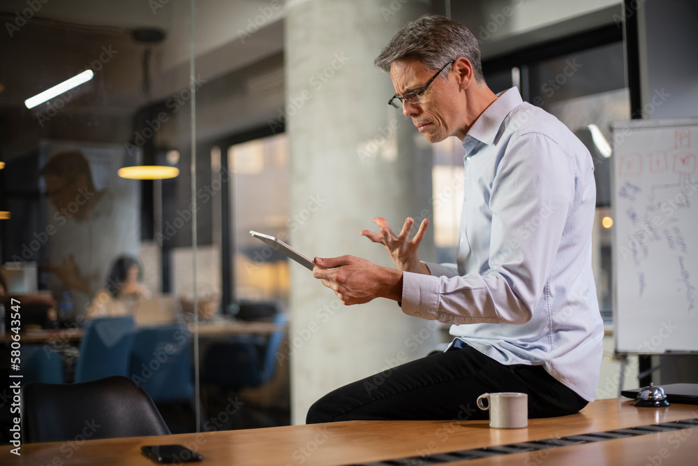 Fototapeta premium Portrait of businessman in office. Man using digital tablet. Businessman having video call.