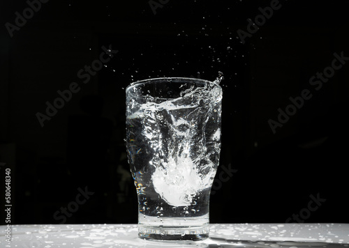 the scene of an ice cube falling into a cup