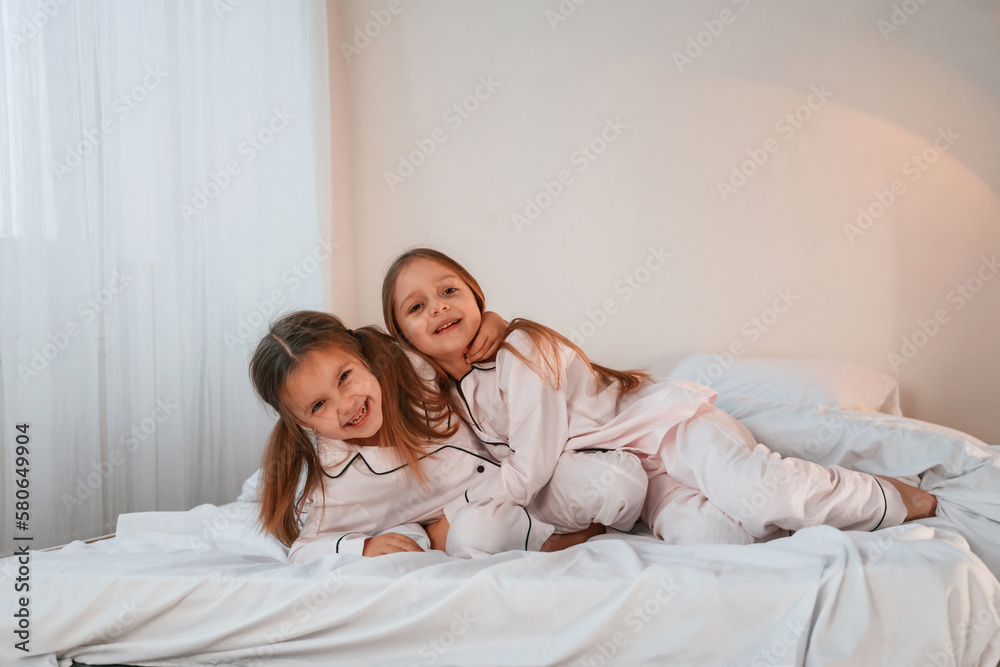 Cheerful and positive two little girls are playing and having fun together in bedroom