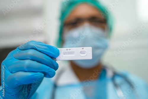 Asian doctor holding Saliva Antigen Test Kit for check Covid19 coronavirus in hospital.
