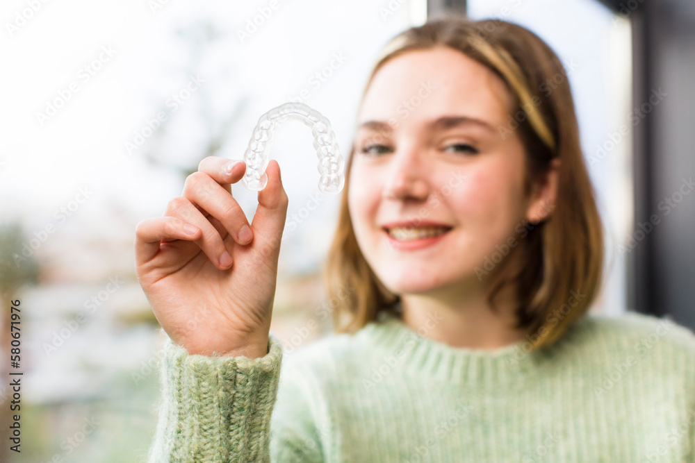 pretty young woman holding a dental retainer. house interior design pretty young woman holding a dental retainer. house interior design