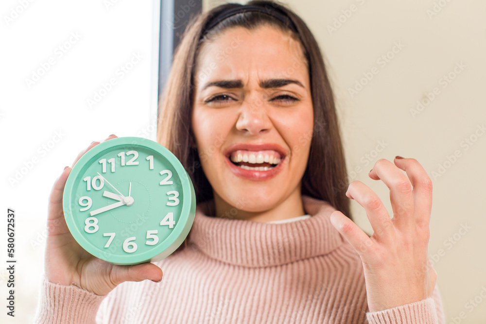 pretty young woman wholding an alarm clock. house interior design pretty young woman wholding an alarm clock. house interior design