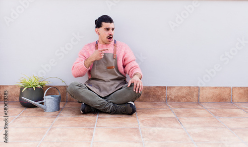 young handsome man gardering and sitting on the floor outdoors © kues1