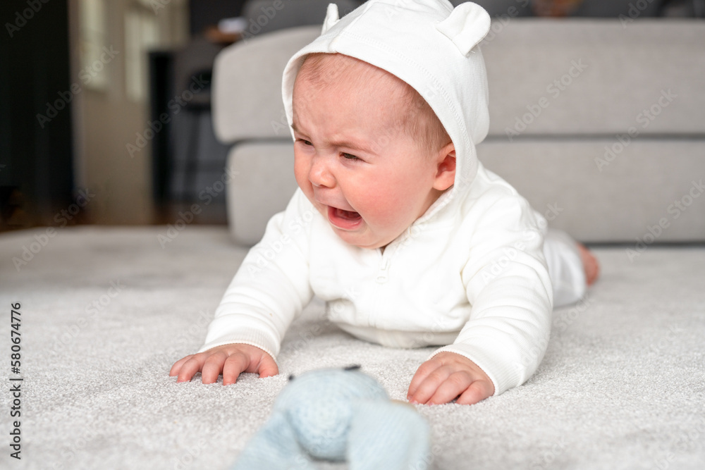 childhood, babyhood and people concept - little baby boy or girl crying lying on floor at home childhood, babyhood and people concept - little baby boy or girl crying lying on floor at home