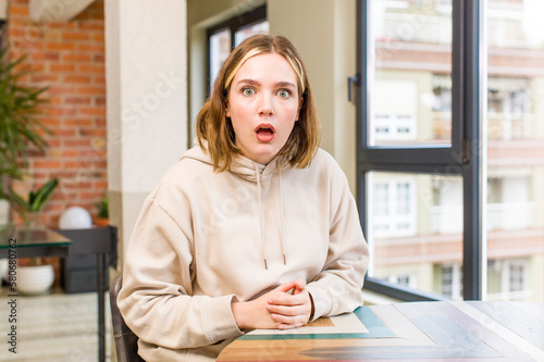 pretty caucasian woman looking very shocked or surprised, staring with open mouth saying wow. home interior concept