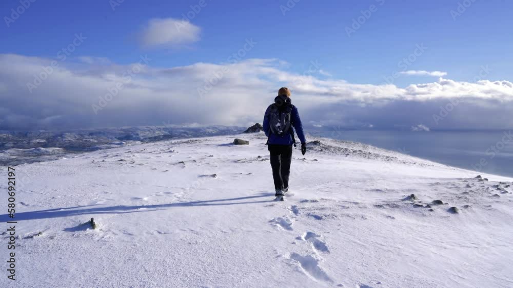 Male hiker walking through the snow on the summit of the Cuillin Mountains in Scotland Male hiker walking through the snow on the summit of the Cuillin Mountains in Scotland