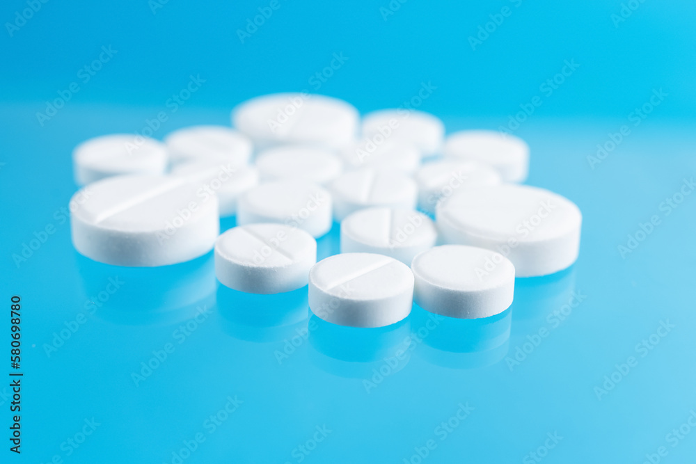 White therapeutic pills or drugs for treatment on blue background, medicine and healthcare concept, close-up view White therapeutic pills or drugs for treatment on blue background, medicine and healthcare concept, close-up view