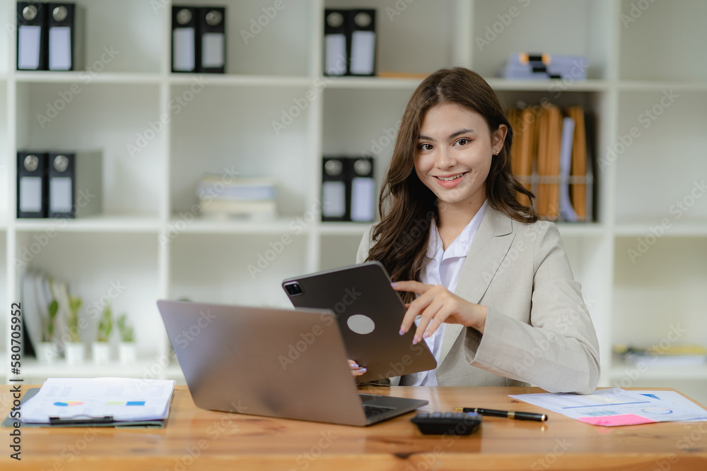 Female accountant working on laptop and doing paperwork, tax, exchange, accounting and financial advisor looking at camera