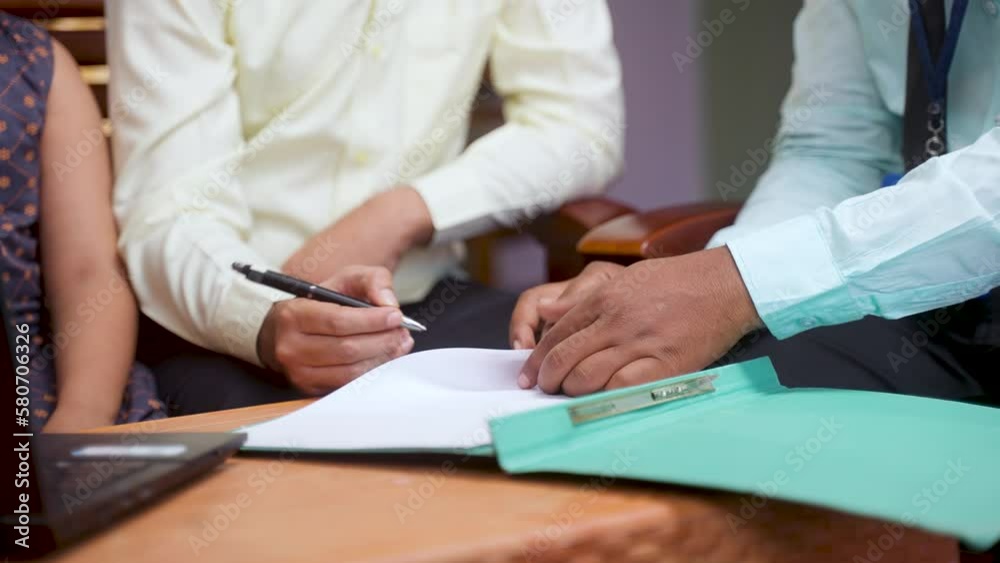 Close up shot of bank officer taking sign from middle aged man for loan of policy insurance documents at home - concept of financial support, selling insurance and doorstep banking