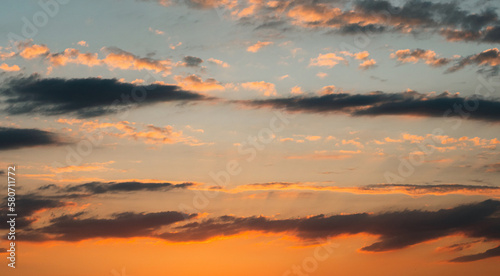 An unbelievably beautiful summer sunset. Yellow-orange clouds against a barely blue sky. The sun's rays from below illuminate the clouds. The beauty of nature. A summer sunset. © VeNN