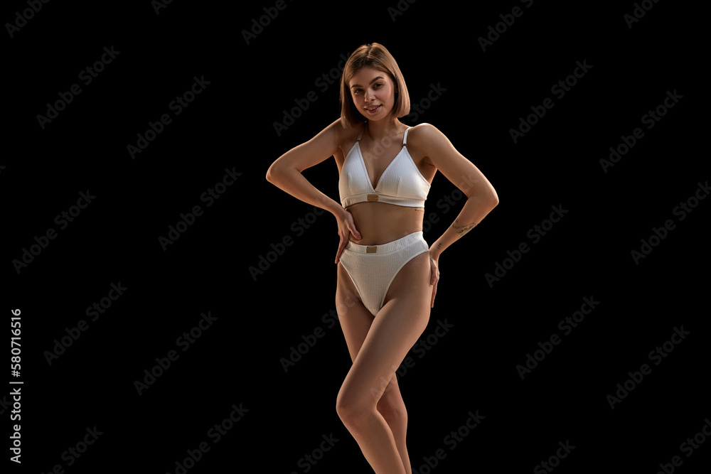 Beauty portrait of young Caucasian blonde woman posing in white color underwear isolated over dark background. Concept of beauty, body and skin care, health, spa, cosmetics, ad