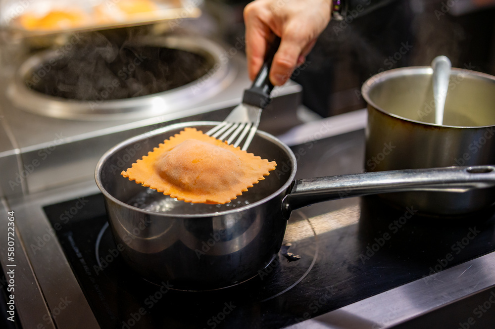 man chef hand cooking one big Ravioli with sauce on restaurant kitchen man chef hand cooking one big Ravioli with sauce on restaurant kitchen