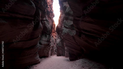 Motion along narrow deep slot canyon with smooth curves red sandstone rocks. Wavy walls of mysterious cave formed by erosion and rainfall. Antelope Canyon is popular place for photos and travel people