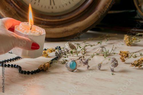 female hand holds a burning candle on a light natural background. pagan wiccan, slavic traditions. Witchcraft, esoteric spiritual ritual for mabon, halloween, samhain