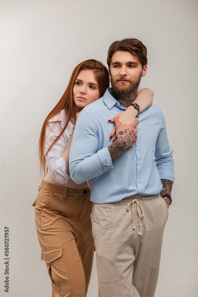 Fashionable beautiful young woman and stylish man in the studio. Fashion couple. Redhead girl and hipster guy in elegant clothes Fashionable beautiful young woman and stylish man in the studio. Fashion couple. Redhead girl and hipster guy in elegant clothes