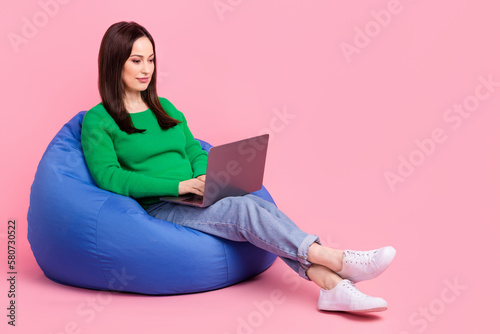 Full body portrait of pretty lady sit comfy bag use netbook online order isolated on pink color background