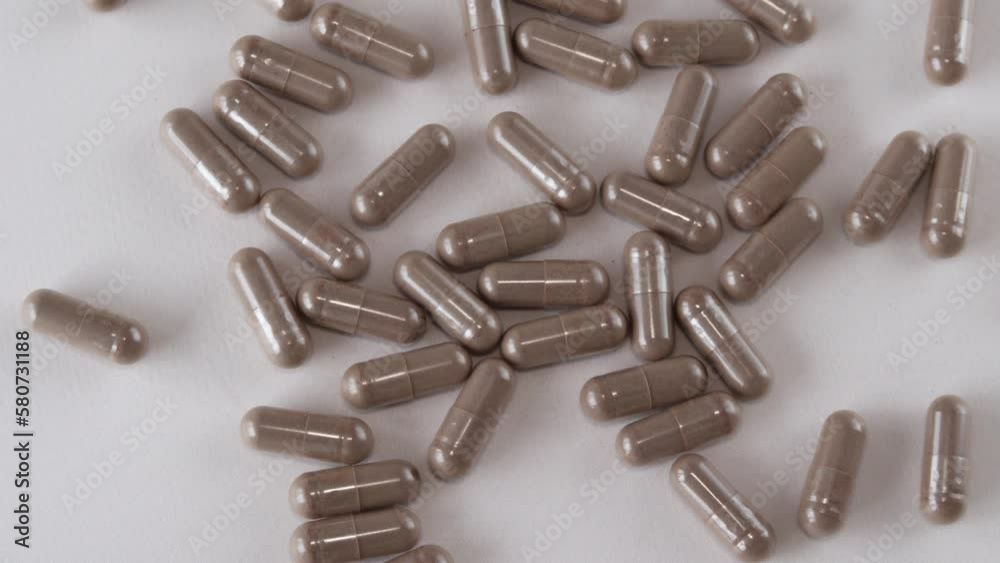 Gray-brown health capsules on a beige background. Dietary supplements and pills in a spoonful. Gray-brown health capsules on a beige background. Dietary supplements and pills in a spoonful.