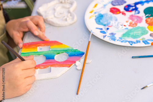 A child painting a piece of paper with a paint brush.