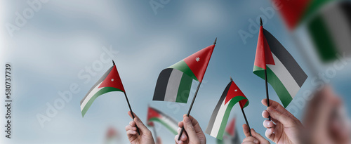 A group of people holding small flags of the Jordan in their hands photo