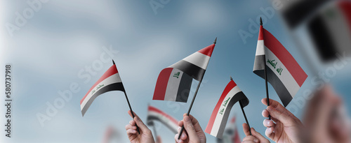A group of people holding small flags of the Iraq in their hands