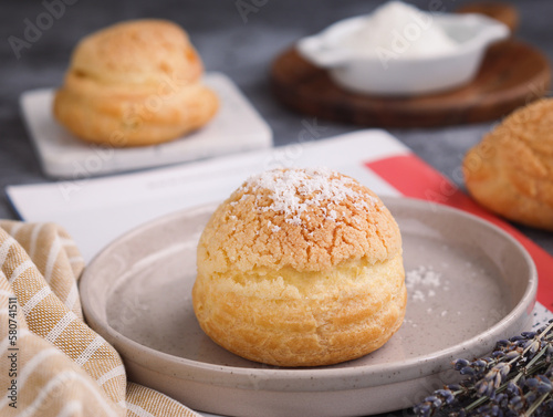 A French cream puff crack bun (Choux au Craquelin) in a plate, topped with grated coconut filling with another choux in background. It's a dessert base of savory choux dough bun  photo