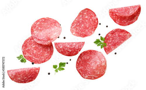 Sliced sausage with parsley leaves and peppercorns are flying on a white background.