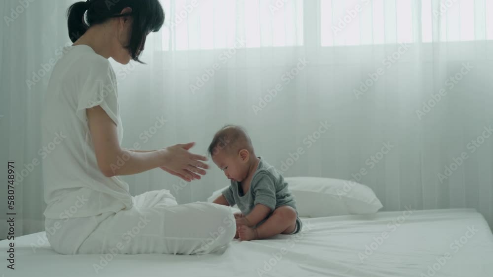 asian mother is training her child to crawl on the bed. The mother is encouraging the child to make an effort to practice her crawling. The concept of development according to age... asian mother is training her child to crawl on the bed. The mother is encouraging the child to make an effort to practice her crawling. The concept of development according to age...